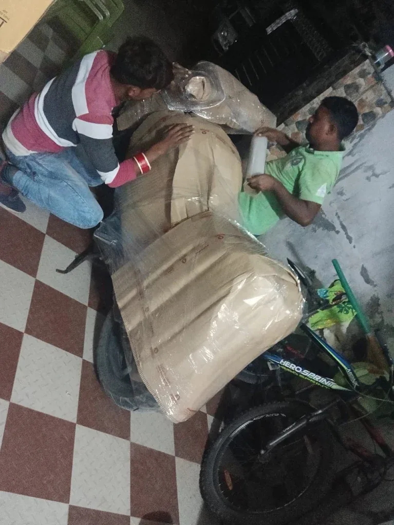 Two Agarwal Packers and Movers workers wrapping a motorcycle before transport from Dehradun