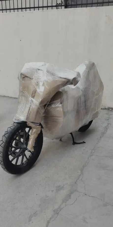 Motorcycle fully wrapped in protective packing material, ready to be loaded for transport